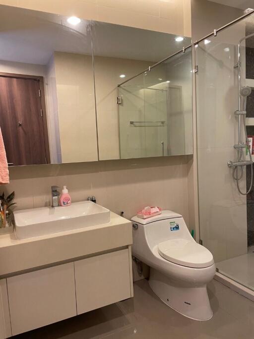 Modern bathroom with glass shower, large mirror, and white fixtures