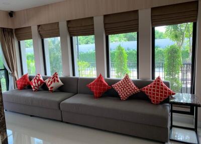 Living room with large windows and gray sofa with red and white pillows