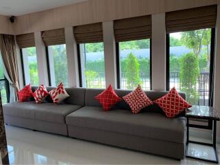 Living room with large windows and gray sofa with red and white pillows