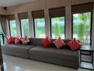 Living room with large windows and gray sofa with red and white pillows