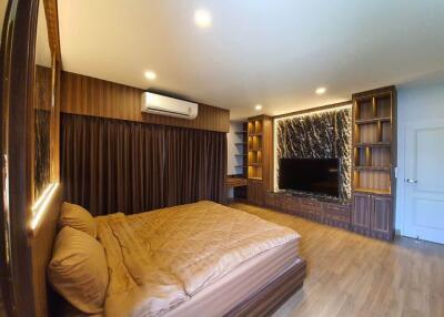 Modern bedroom with large bed, TV, wooden floor, and built-in shelves