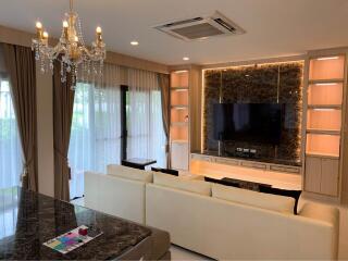 Living room with chandelier, TV, and large windows with curtains