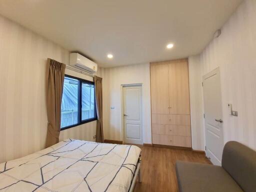 Cozy bedroom with double bed, built-in closet, and split air conditioner