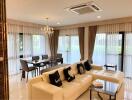 Modern living room with adjoining dining area featuring large windows, chandelier, and air conditioning