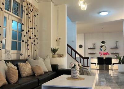 Modern living room with black leather couch, coffee table, and contemporary lighting.