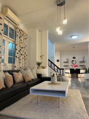 Modern living room with black leather couch, coffee table, and contemporary lighting.