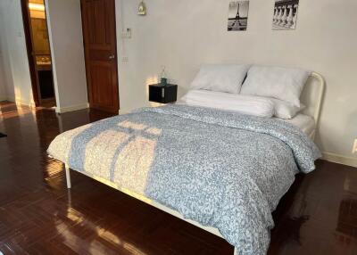 Spacious bedroom with a double bed, hardwood floor, and decor above the headboard