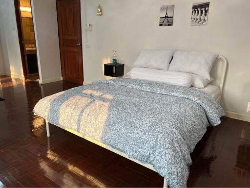 Spacious bedroom with a double bed, hardwood floor, and decor above the headboard