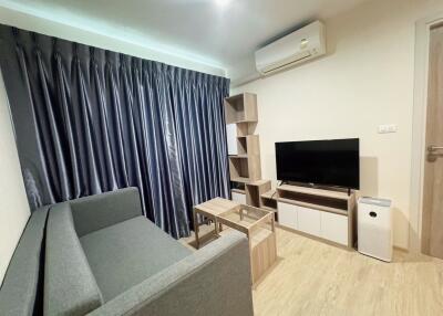 Living room with grey sofa, TV, and wooden furniture