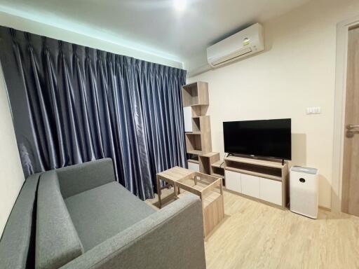 Living room with grey sofa, TV, and wooden furniture