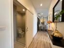 Bright hallway with wooden flooring, leading to a dining area with modern decor