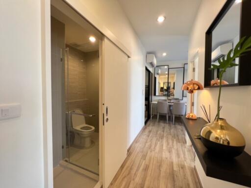 Bright hallway with wooden flooring, leading to a dining area with modern decor