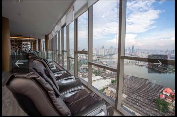 Lounge area with massage chairs and cityscape view through large windows