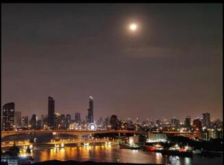 Night view of city skyline with illuminated buildings and a full moon