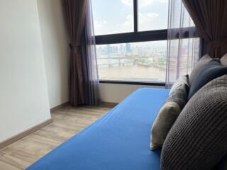 Bedroom with a blue bedspread, large window, and city view