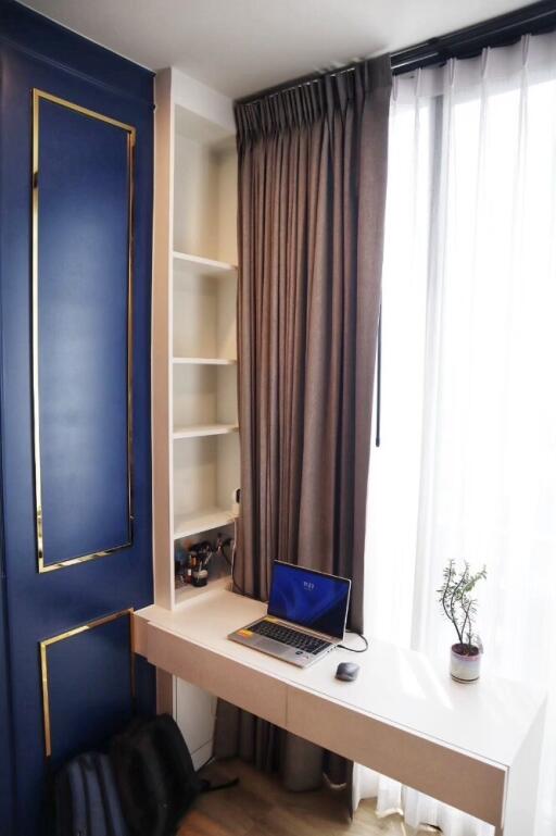 Home office area with desk, laptop, shelves, and window