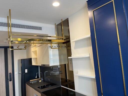 Modern kitchen with blue and gold accents, displaying cabinetry and appliances