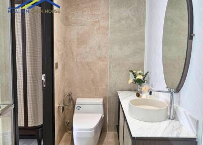 Modern bathroom with a toilet, decorative sink, and large mirror