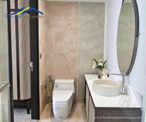 Modern bathroom with a toilet, decorative sink, and large mirror