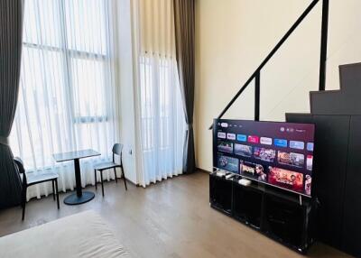 Modern living room with high ceilings, large windows, and a mounted TV