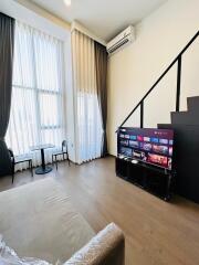 Modern living room with high ceilings, large windows, and a mounted TV