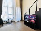 Modern living room with high ceilings, large windows, and a mounted TV