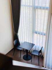 Small dining area with table and chairs near large windows