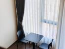 Small dining area with table and chairs near large windows