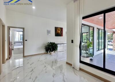 Modern living space with glossy marble flooring, large windows, and indoor-outdoor space connection