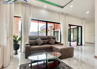 Modern living room with large windows, sofa, and glass coffee table