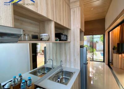 Modern kitchen with wooden finishes, double sink, and outdoor view