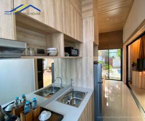 Modern kitchen with wooden finishes, double sink, and outdoor view