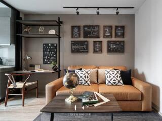 A modern living room with a brown sofa, wall decorations, a coffee table and a desk area.