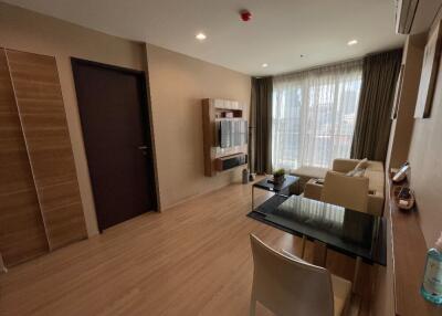 Modern living room with neutral colors, a mounted TV unit, and large windows with sheer curtains