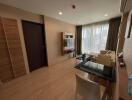 Modern living room with neutral colors, a mounted TV unit, and large windows with sheer curtains