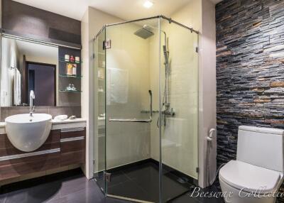 Modern bathroom with glass shower and stone accent wall