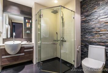 Modern bathroom with glass shower and stone accent wall