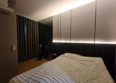 Modern bedroom with striped bedding, mirrored wall, and ambient lighting