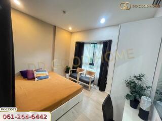 Cozy bedroom with a large orange bed, two chairs by the window, study desk, and potted plant