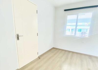 Empty bright bedroom with large window and wooden flooring