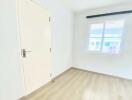 Empty bright bedroom with large window and wooden flooring