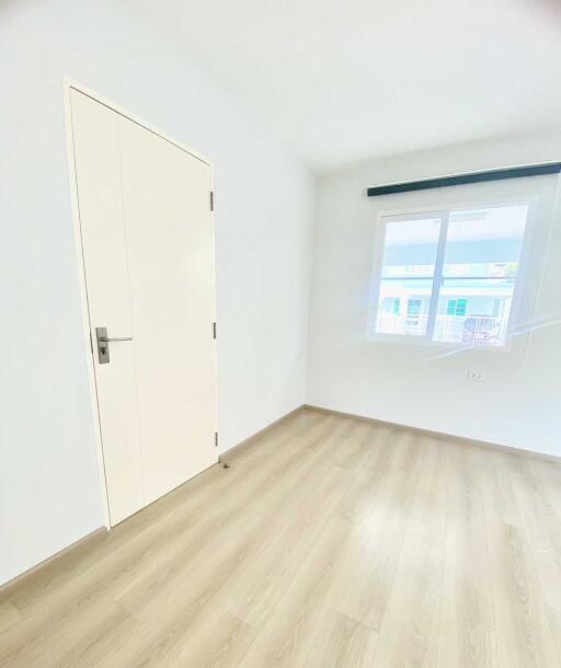 Empty bright bedroom with large window and wooden flooring