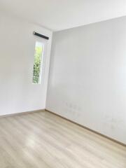 Empty bedroom with wooden flooring and a window