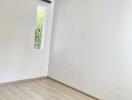 Empty bedroom with wooden flooring and a window