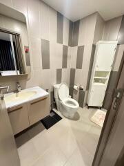 Modern bathroom with sink, toilet, mirror, and storage cabinet