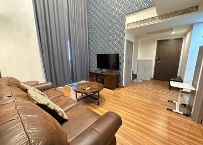 Spacious living room with a brown leather couch and a flat-screen TV