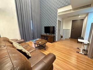 Spacious living room with a brown leather couch and a flat-screen TV