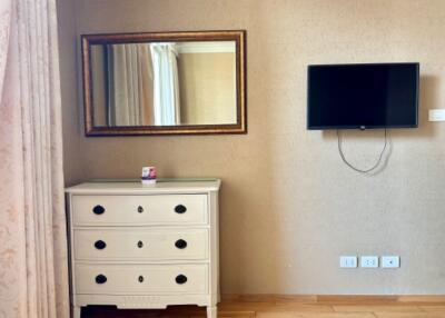 Bedroom with dresser, mirror, and mounted TV