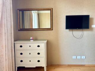 Bedroom with dresser, mirror, and mounted TV