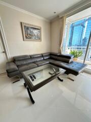 Modern living room with leather sectional sofa and glass coffee table next to a large window